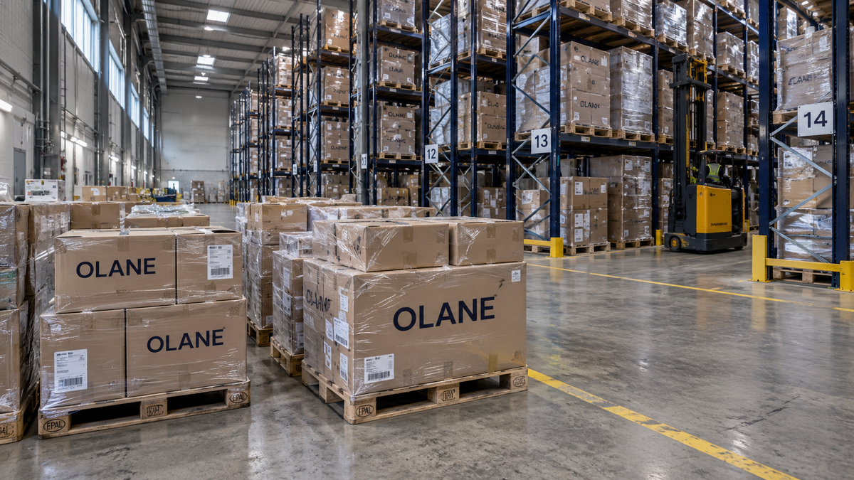 OLANE warehouse cross-aisle with navy-branded inventory cartons and tall stocked navy racks